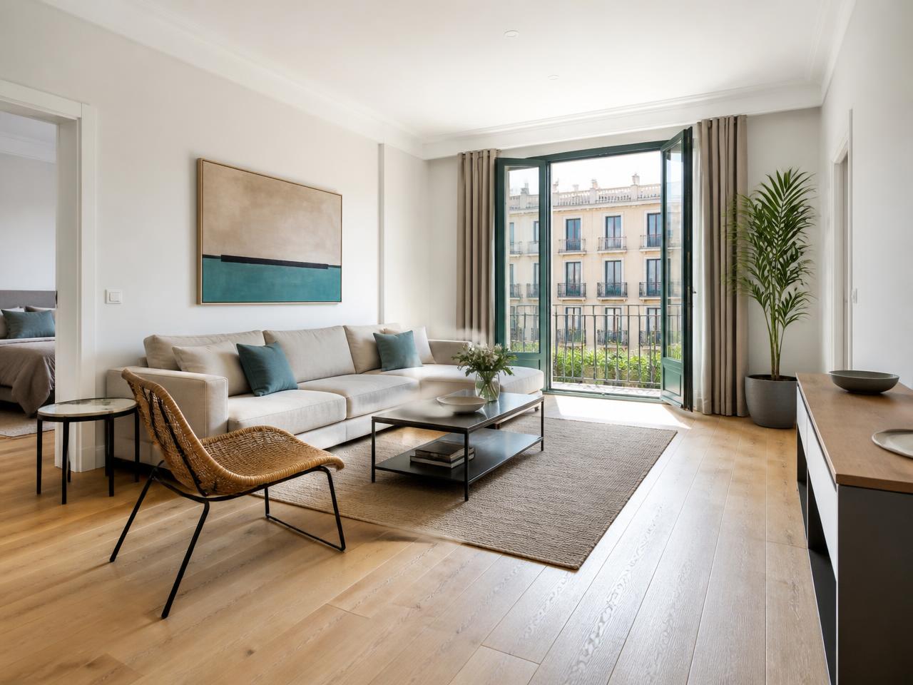 Salón de una vivienda reformada en Barcelona con suelo de madera clara y balcón